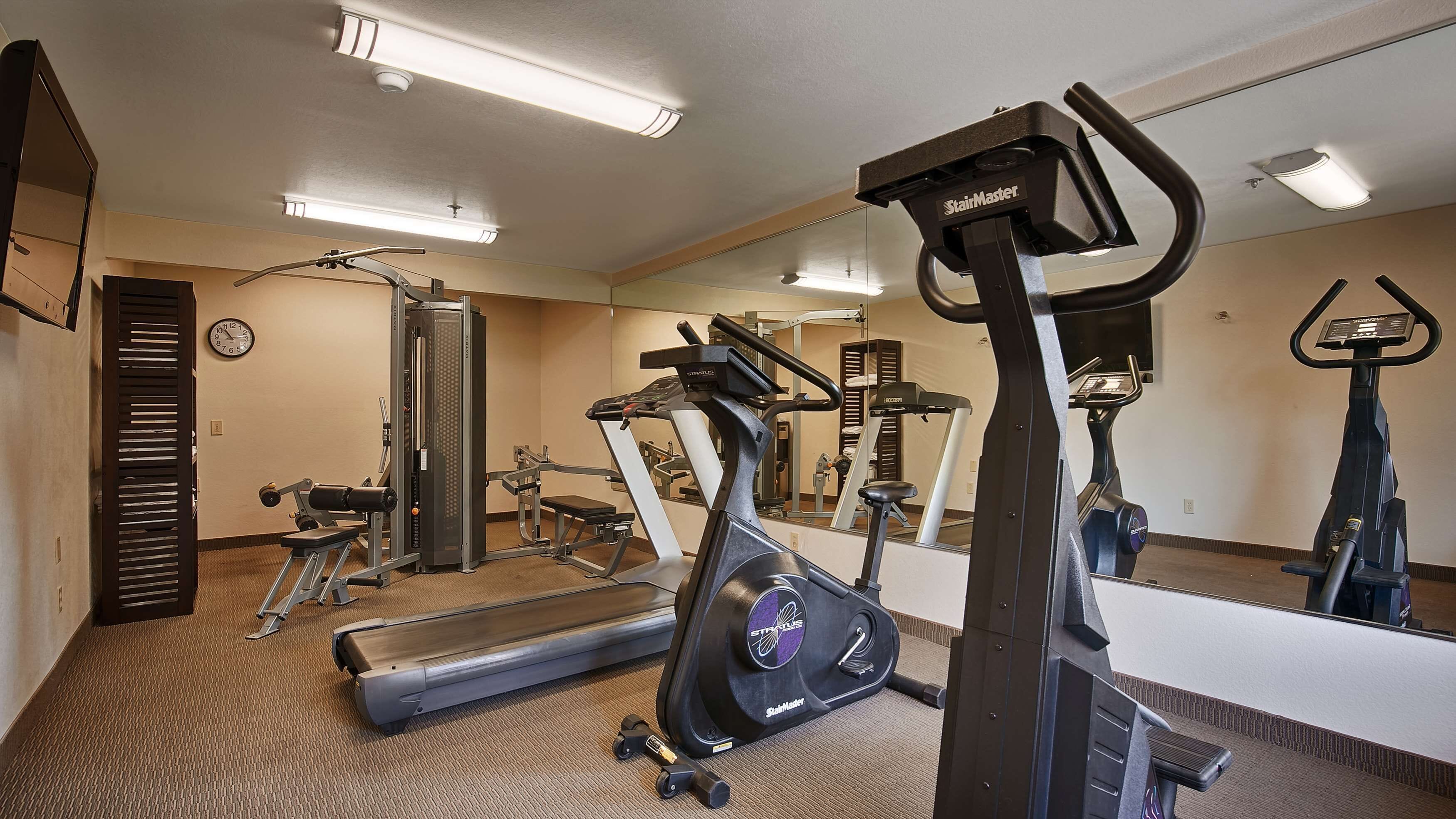 Un gimnasio con cintas de correr, elípticas y equipo de pesas.