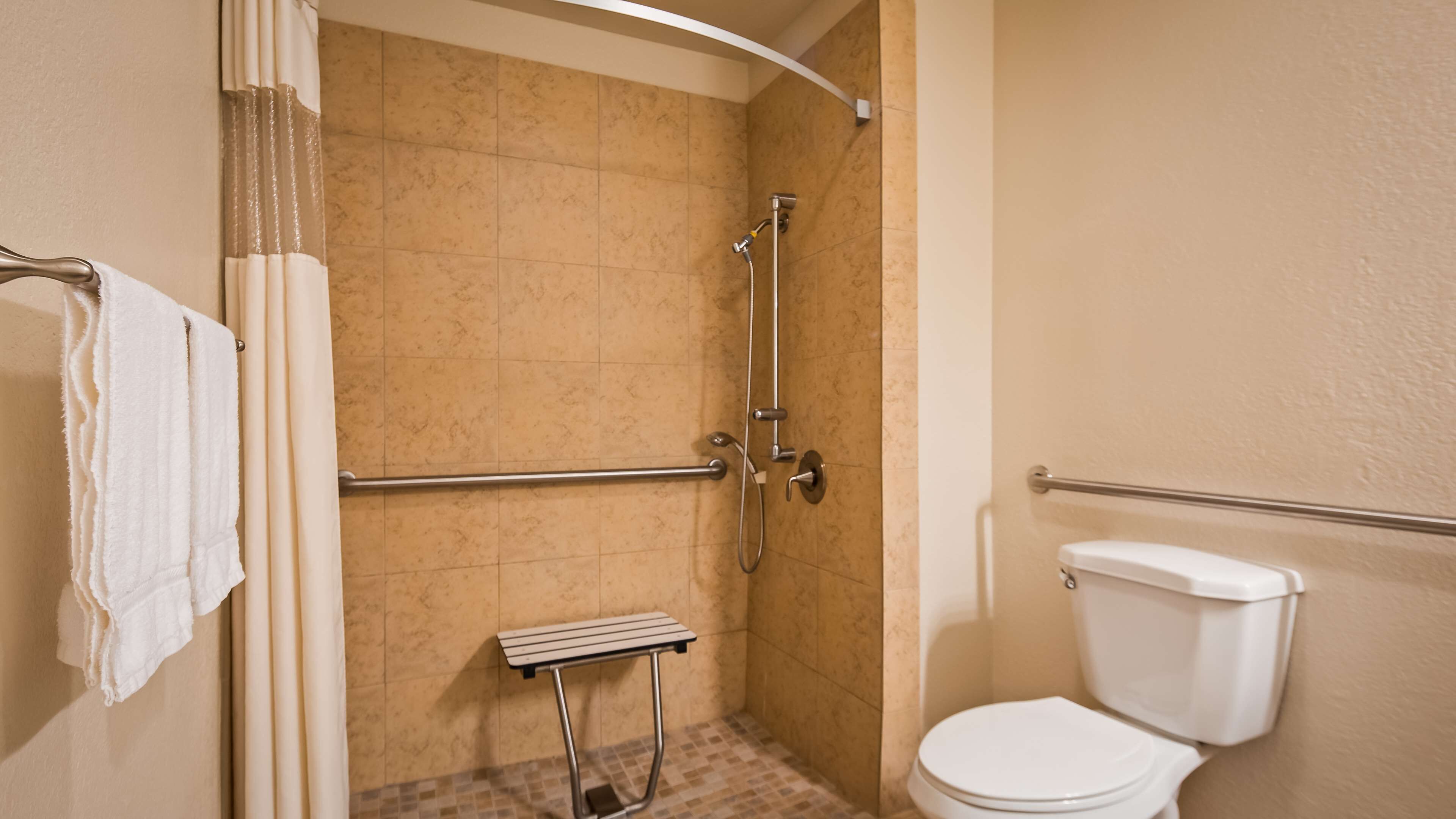 A bathroom with a shower, grab bar, and toilet.