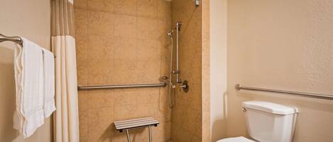 Un baño con ducha, barra de apoyo y retrete.