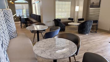 A modern lounge area with marble-topped tables, leather sofas, and a mix of seating arrangements.