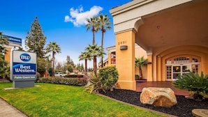 A Best Western Palm Court Inn entrance with a clear sky, palm trees, and a well-maintained lawn.
