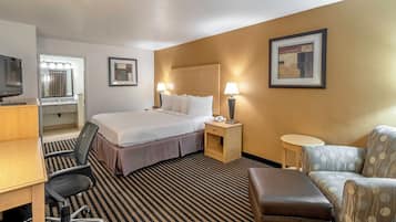 Een hotelkamer met een bed, bureau, stoel en een klein tafeltje.