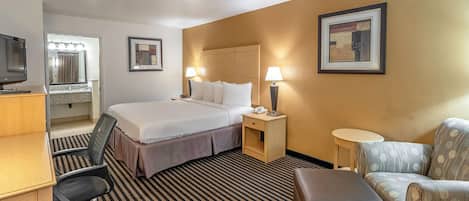 Habitación de hotel con cama, escritorio, silla y una pequeña mesa.