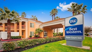 A Best Western Palm Court Inn with a clear entrance, palm trees, and a well-maintained lawn.