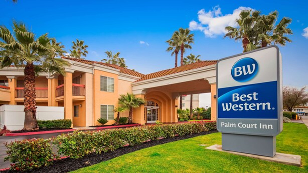 A Best Western Palm Court Inn with a clear entrance, palm trees, and a well-maintained lawn.