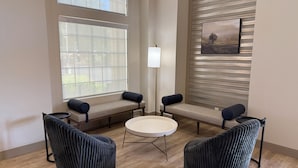 A modern room with a round table, two chairs, a bench, and a floor lamp.
