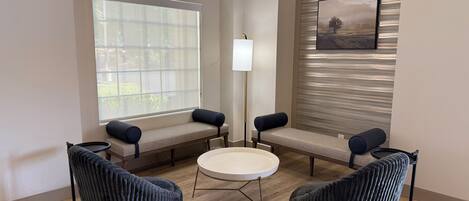 A modern room with a round table, two chairs, a bench, and a floor lamp.