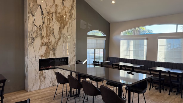 A modern interior with a marble wall, a long dining table, and multiple seating areas.
