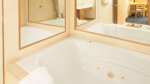 Ein Badezimmer mit einer großen Badewanne, zwei Spiegeln und einem Waschbecken.