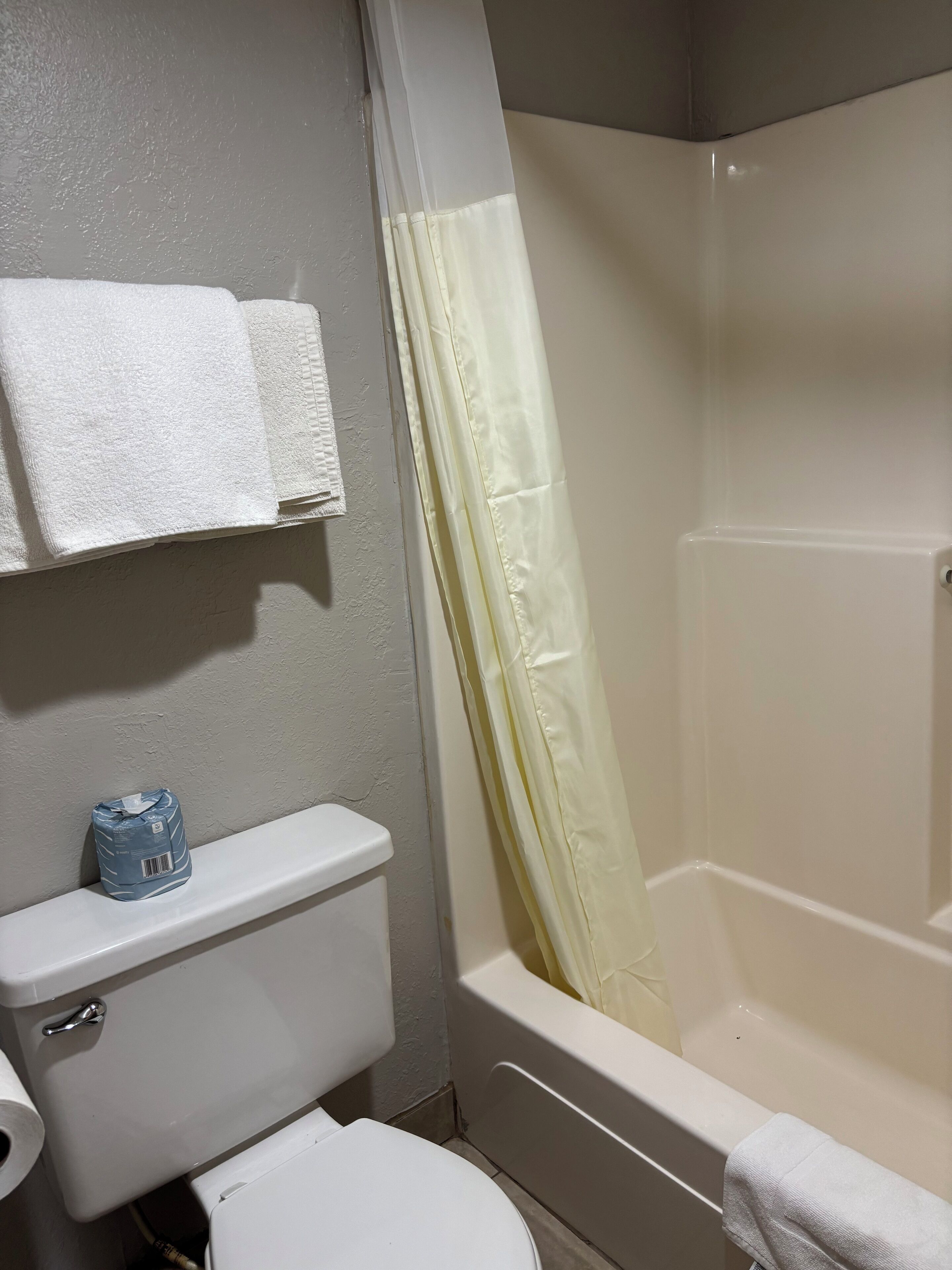 Un baño con inodoro, lavamanos, bañera y cortina de ducha.