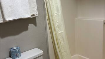 Un baño con inodoro, lavamanos, bañera y cortina de ducha.