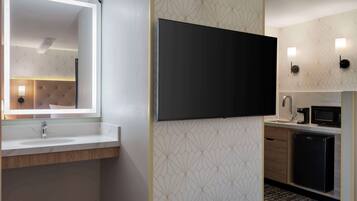 A modern bathroom with a large mirror, a sink, a toilet, and a shower area.