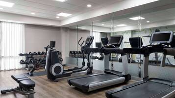 Un gimnasio con cintas de correr, elípticas y una banca.