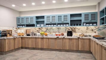 A modern kitchen with marble countertops, wooden cabinets, and blue upper cabinets.