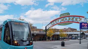 A bus labeled "River Market" approaching a historic city market sign.