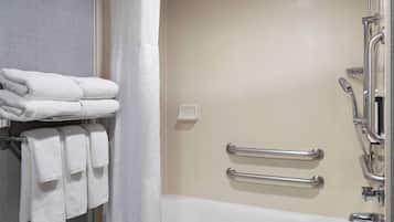 A bathroom with a bathtub, a shower, and a towel rack with folded towels.