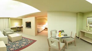 A hotel room with a living area, a dining table with chairs, a TV, a bed, and a small balcony. - Sabe Center Hotel (Asunción)