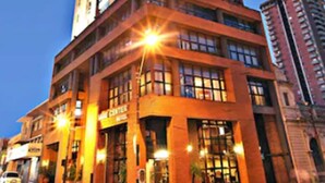 A tall, multi-story hotel with a prominent corner entrance, large windows, and a well-lit facade. - Sabe Center Hotel (Asunción)