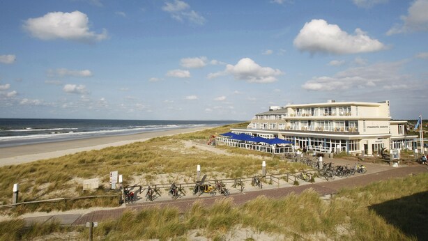 A beachfront hotel with a large building, a sandy beach, and a grassy dune area. - WestCord Strandhotel Seeduyn (Vlieland)