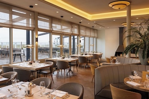 Un restaurante espacioso con amplias ventanas, varias mesas para comer y diversas opciones de asientos.