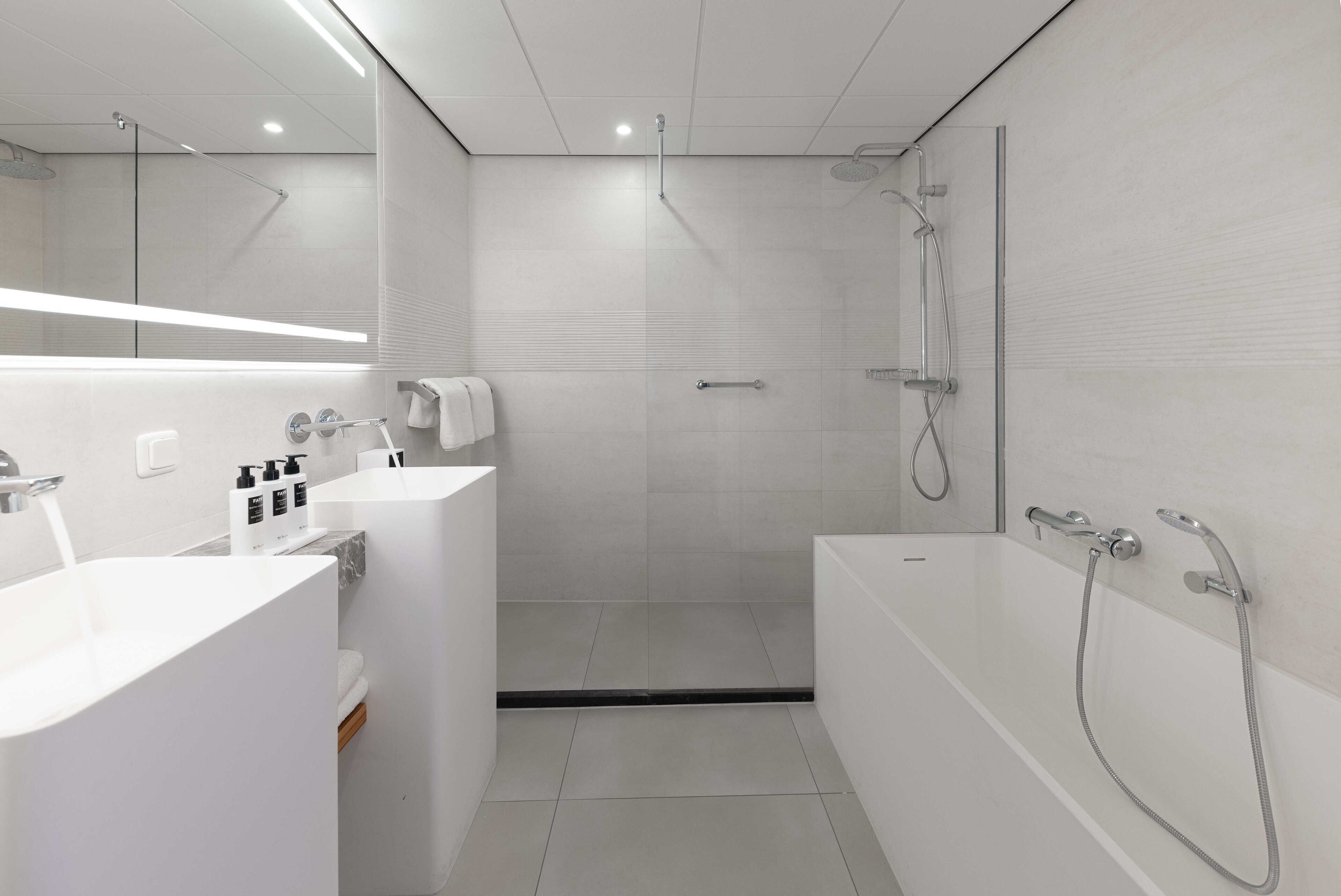 A modern bathroom with a large bathtub, a separate shower area, and a vanity with a mirror and sink.