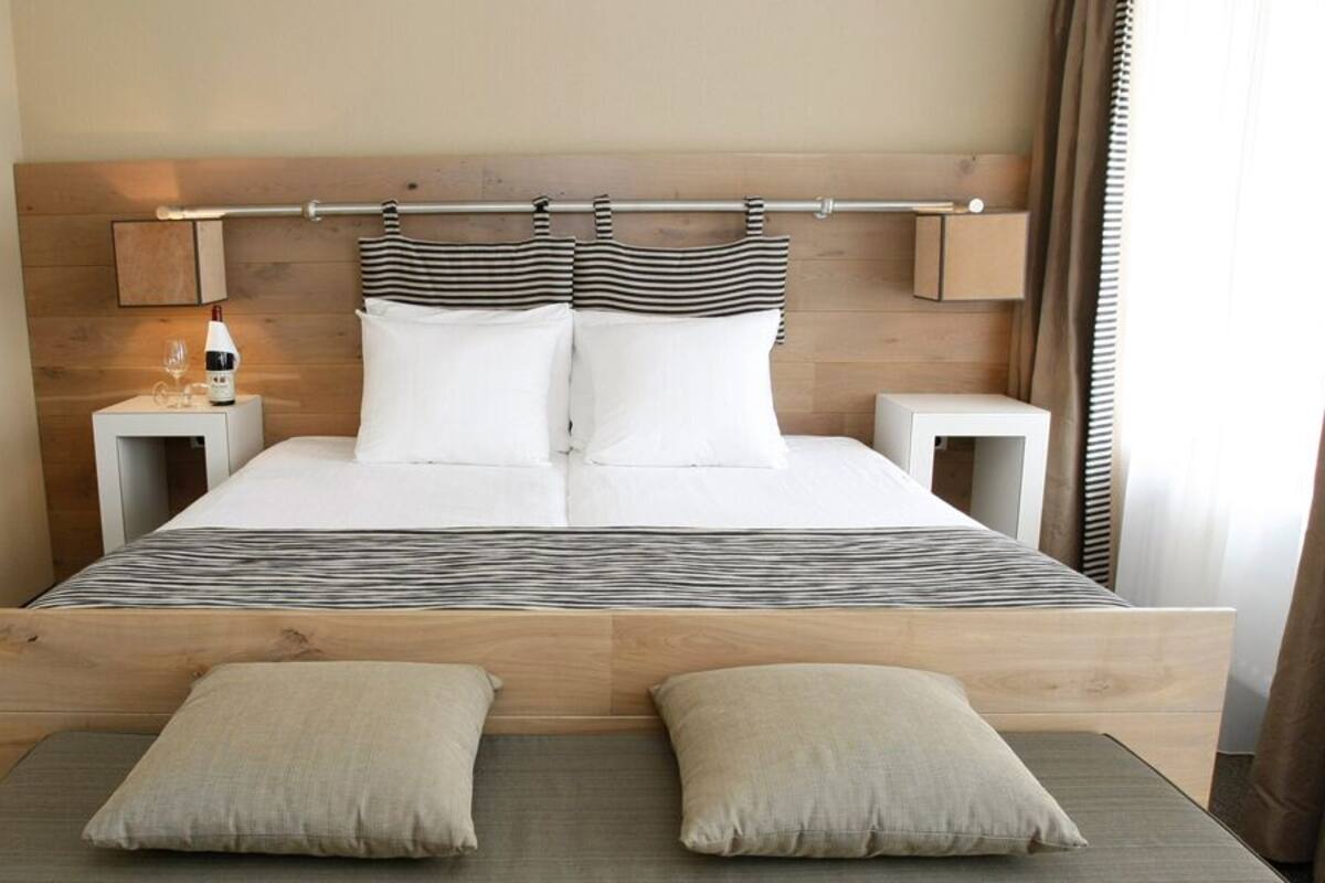A double bed with a wooden headboard, two bedside tables, and a bedside lamp.