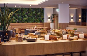 A buffet setup with various food items and containers, including baskets and jars, in a well-lit indoor space with a modern design.