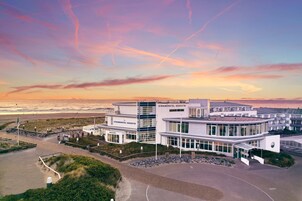 Un hotel moderno con fachada de vidrio, situado cerca de la playa.