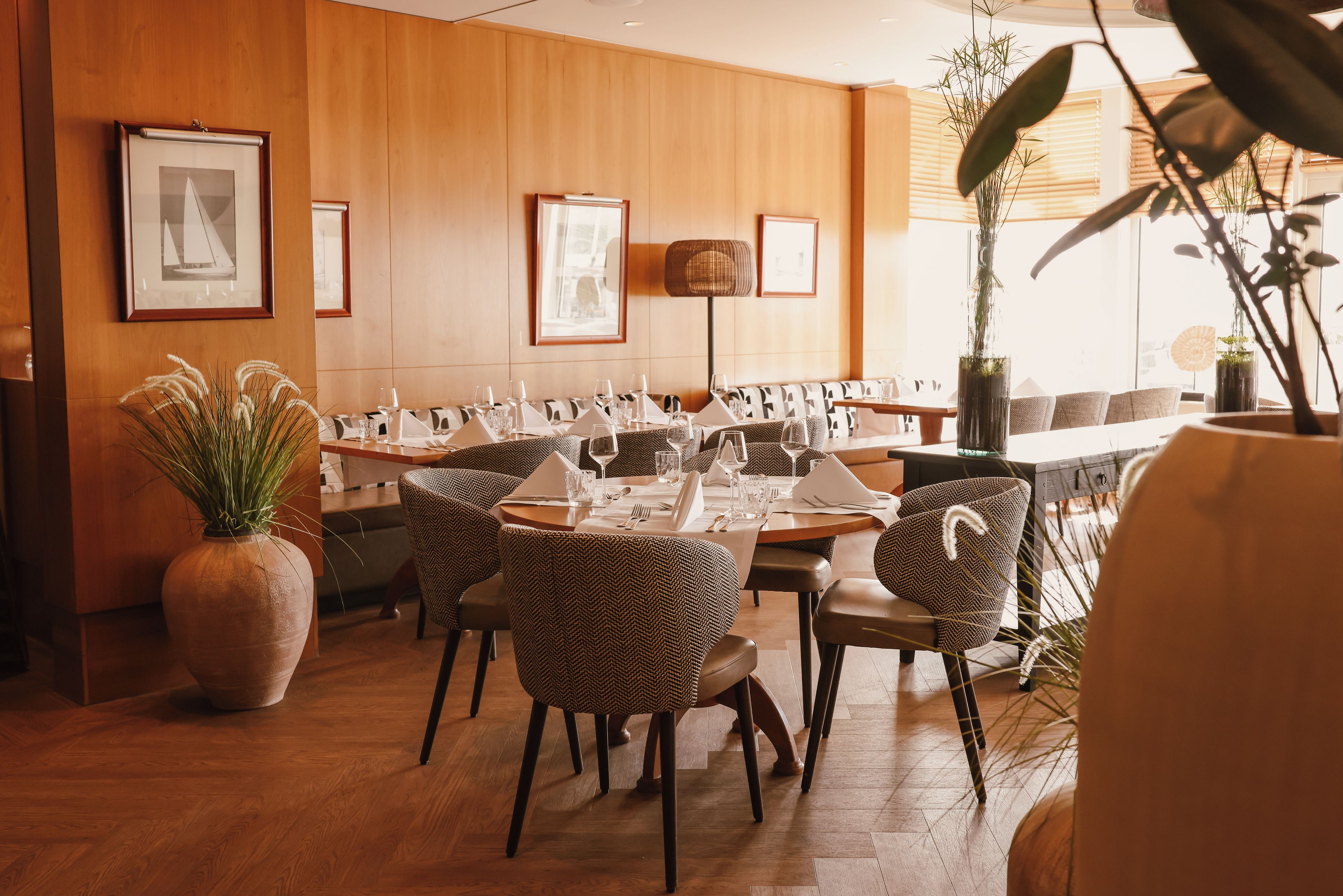 A dining area with wooden panel walls, framed artwork, and a large potted plant.
