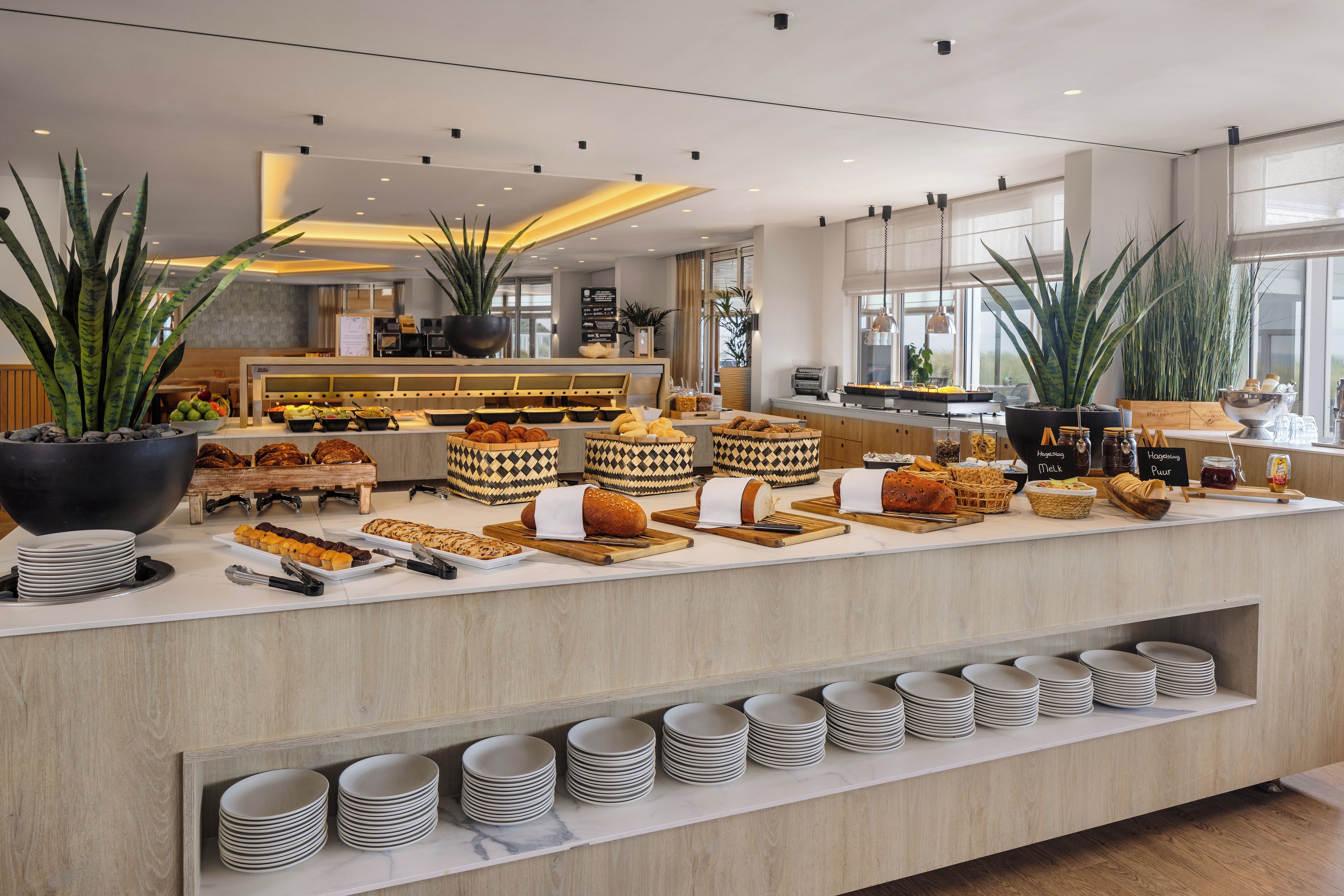 Een buffetgedeelte met diverse gerechten en een assortiment borden en bestek.