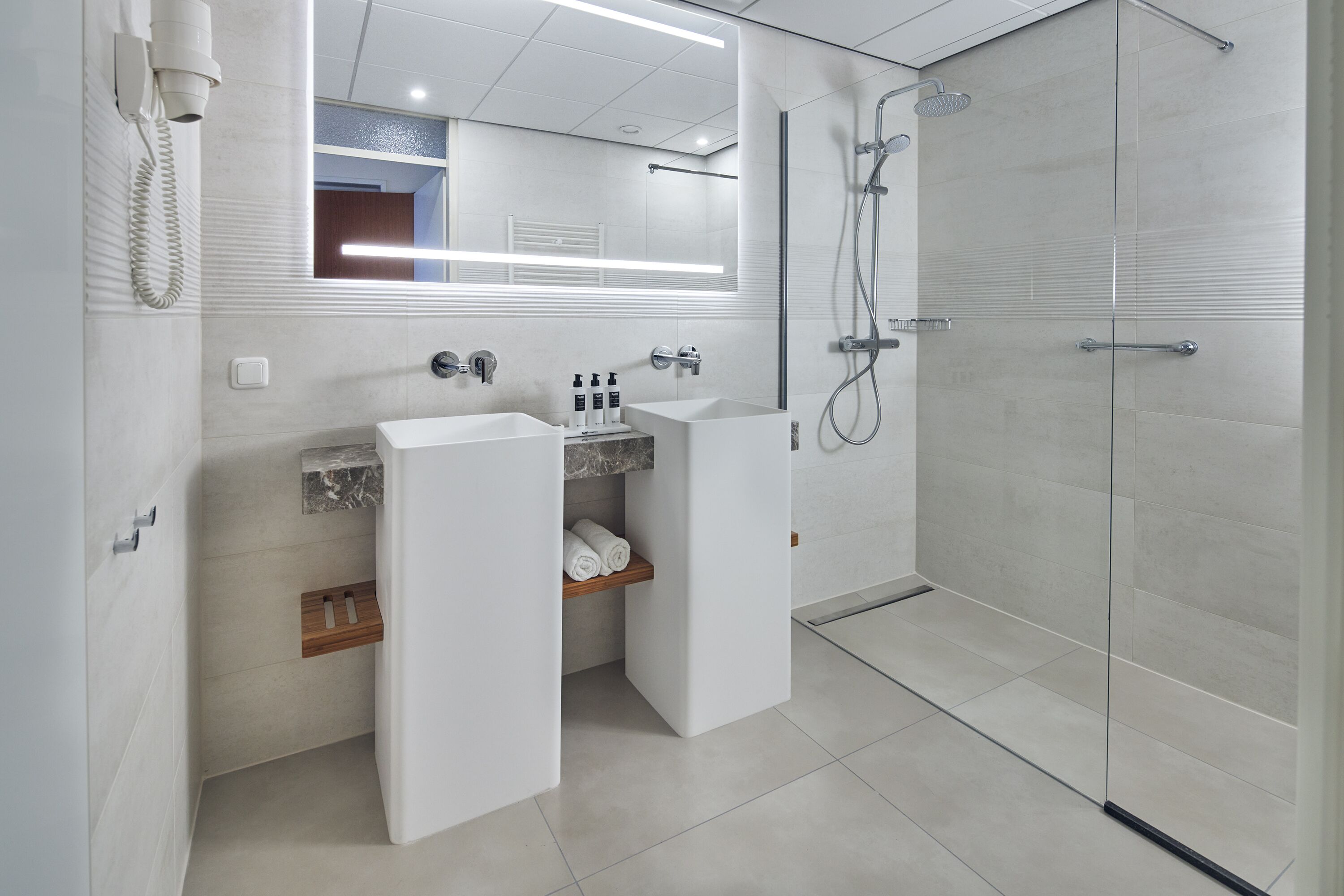 A modern bathroom with a large mirror, a sink, a shower, and a toilet.