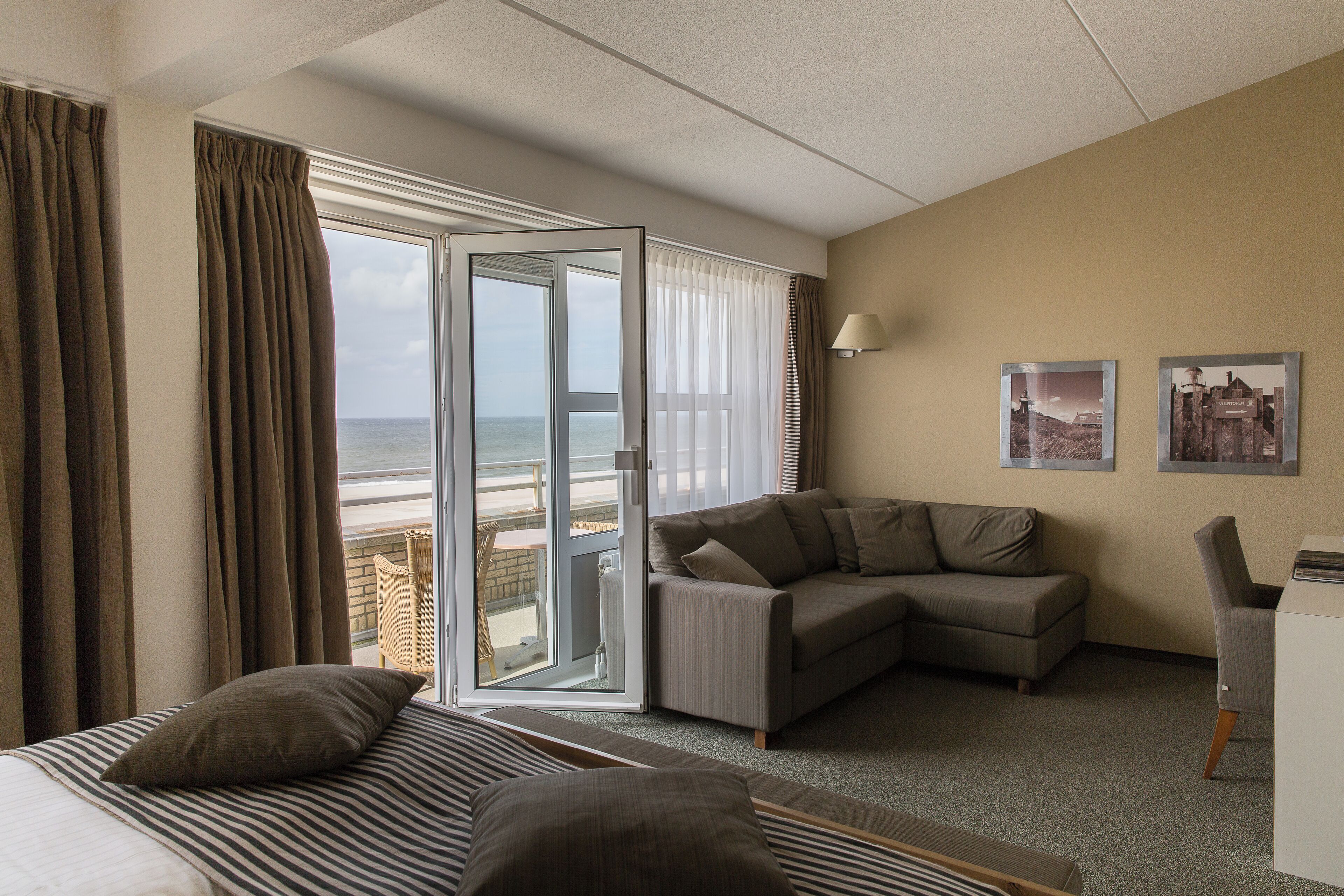A hotel room with a bed, a sofa, a desk, and a view of the ocean.