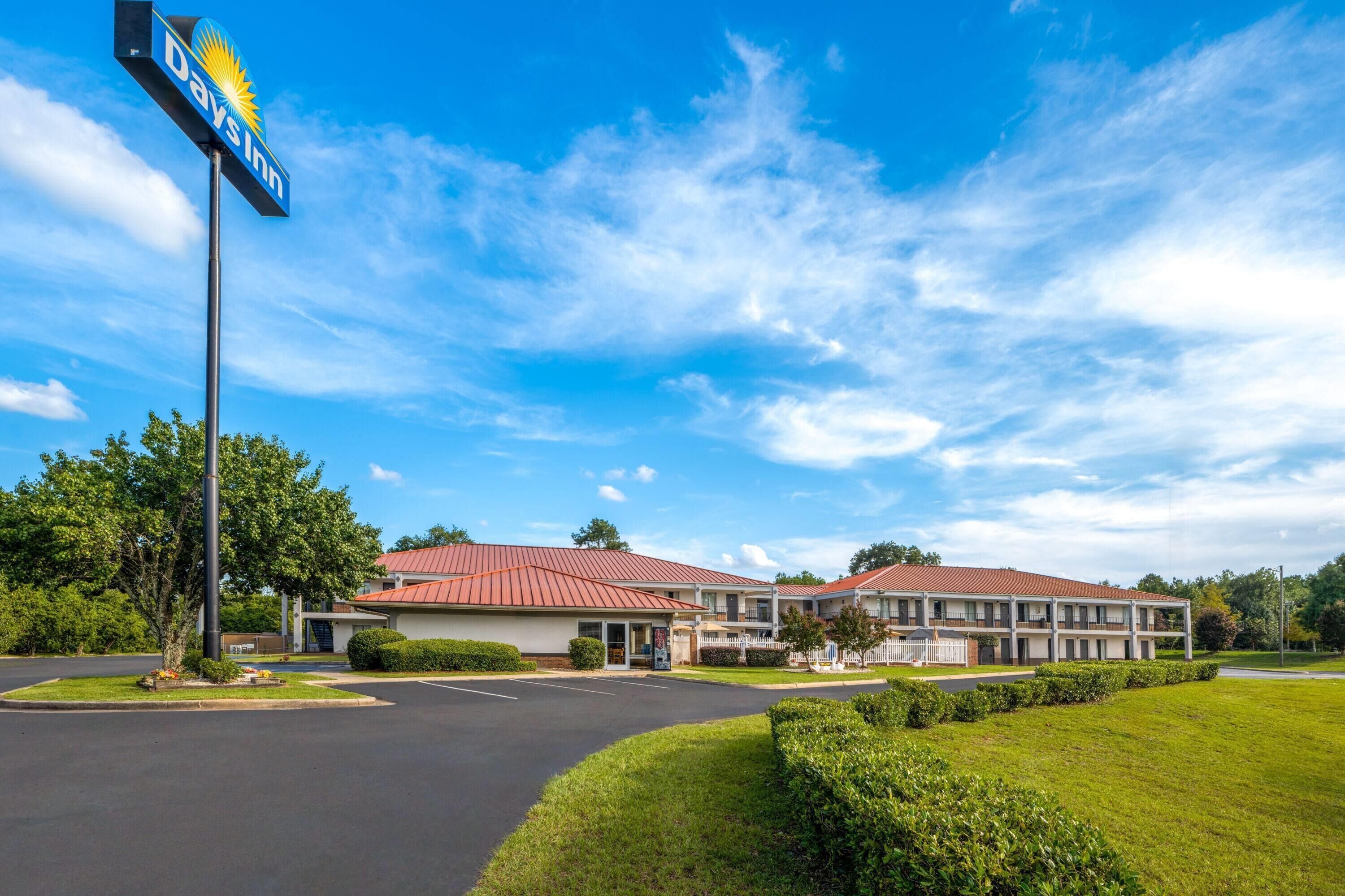 A Days Inn with a red roof, a parking lot, and a well-maintained lawn.