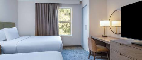 A hotel room with two beds, a desk, a chair, a TV, and a window with curtains.