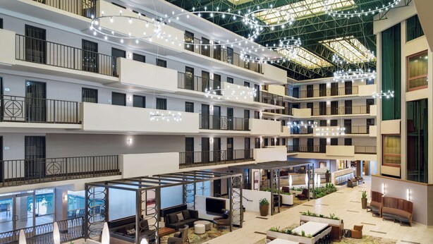 Un hall d’hôtel à plusieurs niveaux, doté d’un espace central ouvert, de coins salon et d’un plafond décoré de guirlandes lumineuses.
