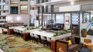 Un hall d’hôtel moderne comprenant un espace repas, des sièges et un escalier menant à l’étage supérieur.