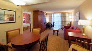 Ein Hotelzimmer mit Esstisch, Stühlen, einer Couch, einem Schreibtisch mit Stuhl, einem Fernseher und einem Bett.