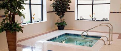 A spa area with a hot tub, potted plants, and a tiled floor.