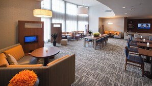 Un hall de hotel con una zona de estar, un televisor y un comedor.