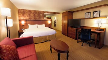 A hotel room with a bed, a desk, a chair, a TV, and a sofa.