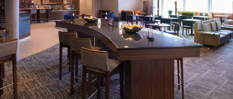A hotel lobby with a bar area, seating arrangements, and a television screen.
