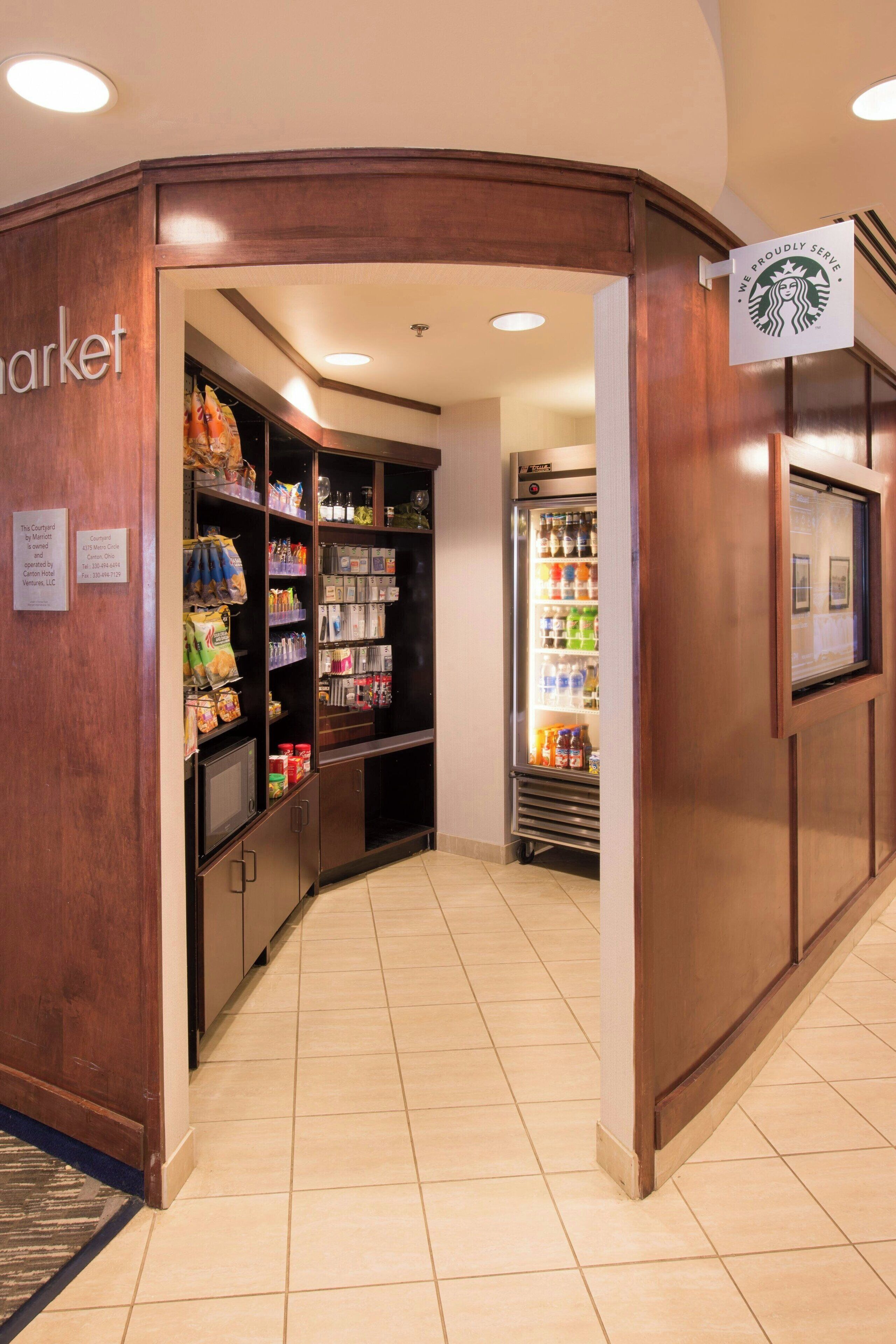 A corner of a hotel lobby with a Starbucks coffee shop, a refrigerator stocked with beverages, and a variety of snacks and toiletries.