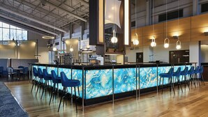 A modern bar area with a marble countertop, blue bar stools, and pendant lighting.