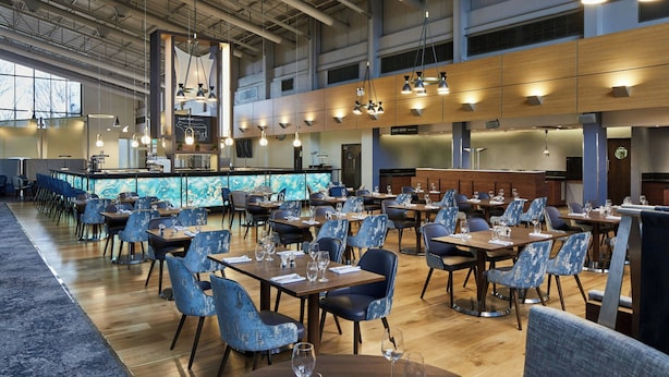 A spacious dining area with high ceilings, modern pendant lighting, and a central bar area.