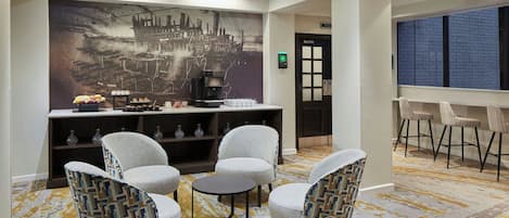 Un espace de détente moderne comprenant un coin café, des sièges et une fresque représentant un paysage urbain.