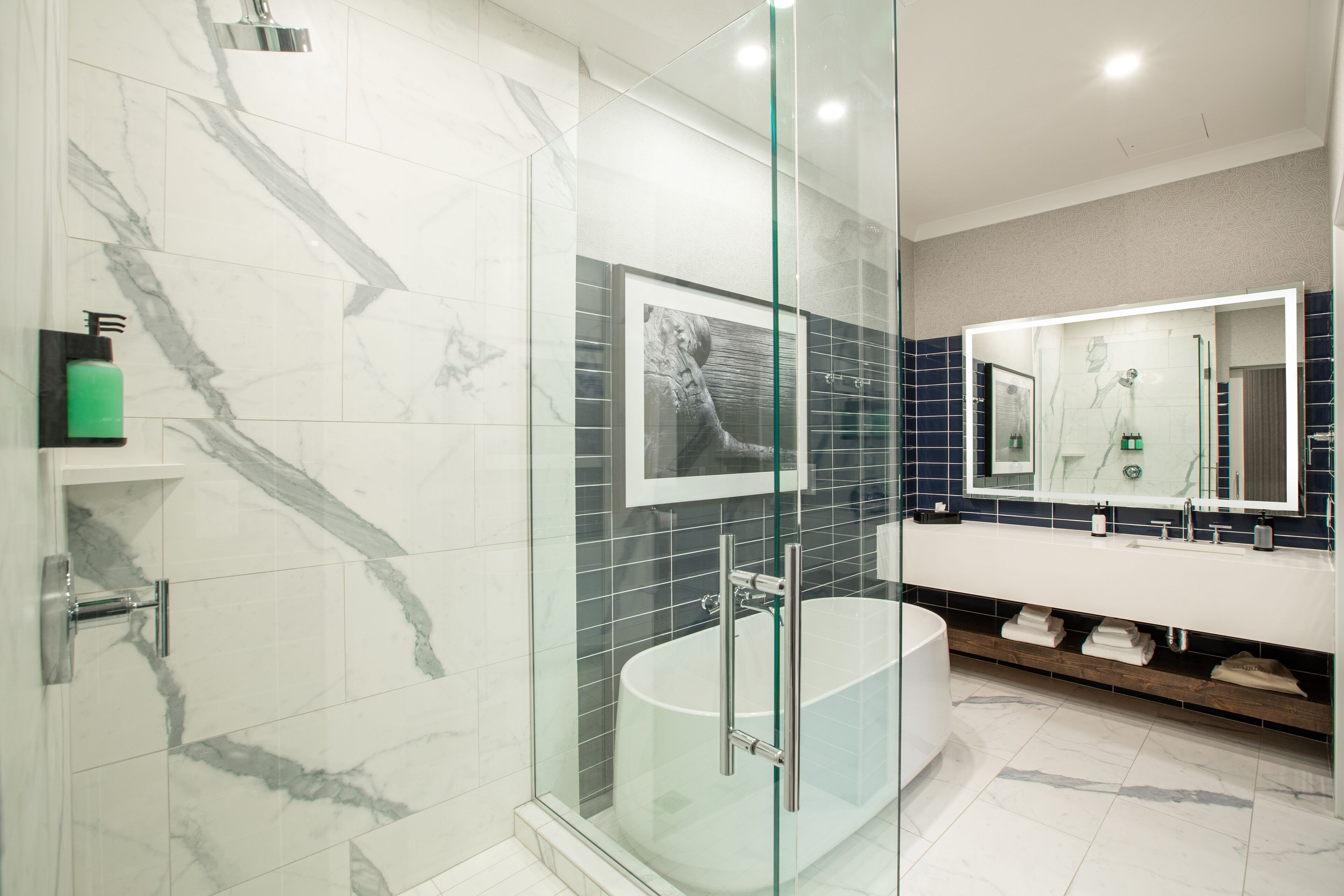 A modern bathroom with a glass-enclosed shower, a freestanding bathtub, and a large mirror above the vanity.