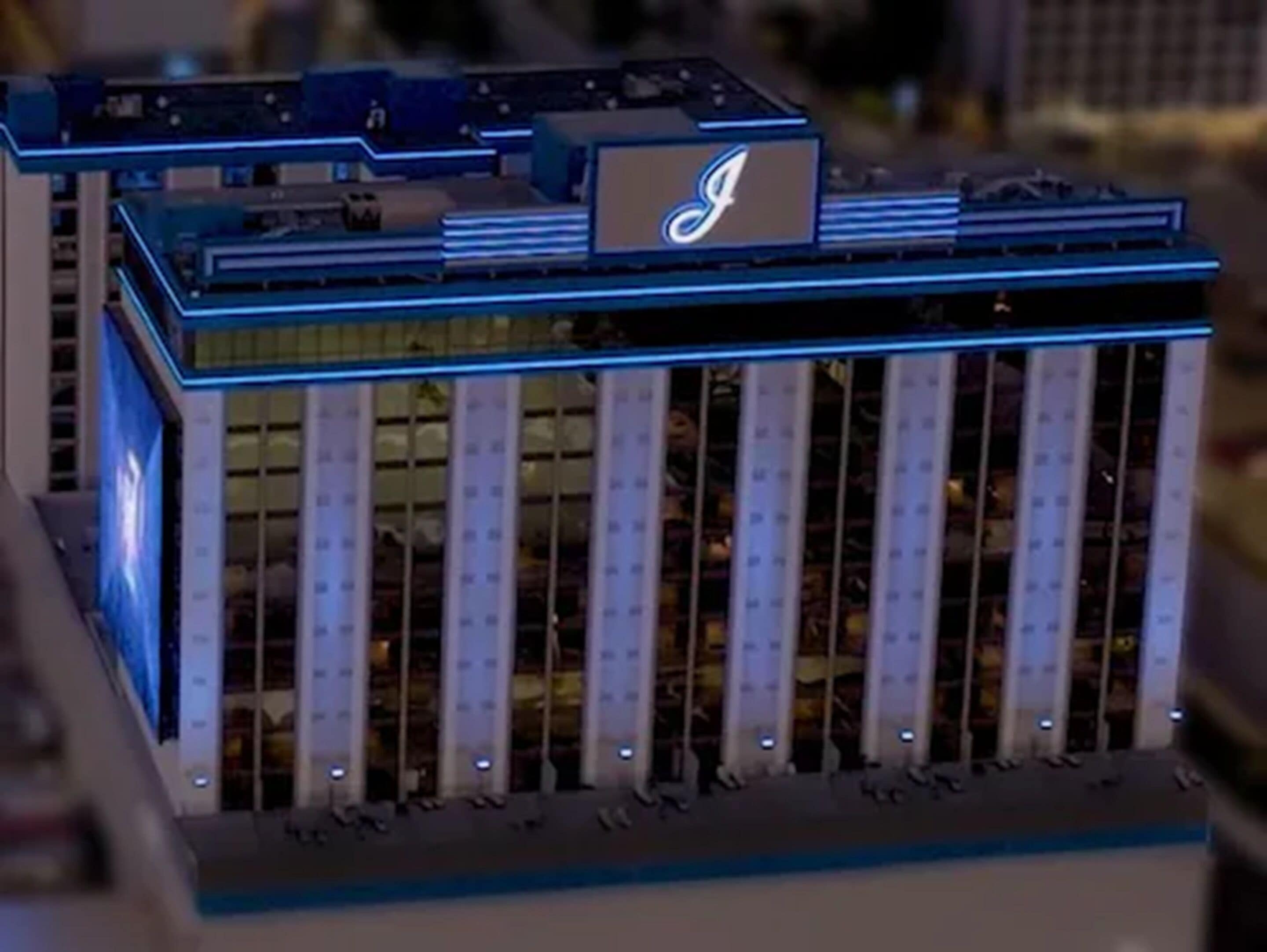Modello di un edificio con un logo 'J' ben visibile sulla facciata, diversi piani e una serie di finestre verticali.
