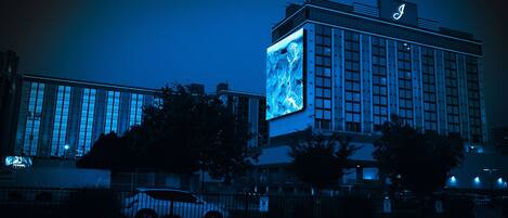 A hotel with a prominent illuminated sign and a large digital display on its facade.