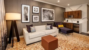 A modern living room with a sofa, a coffee table, and a kitchen area with a microwave.