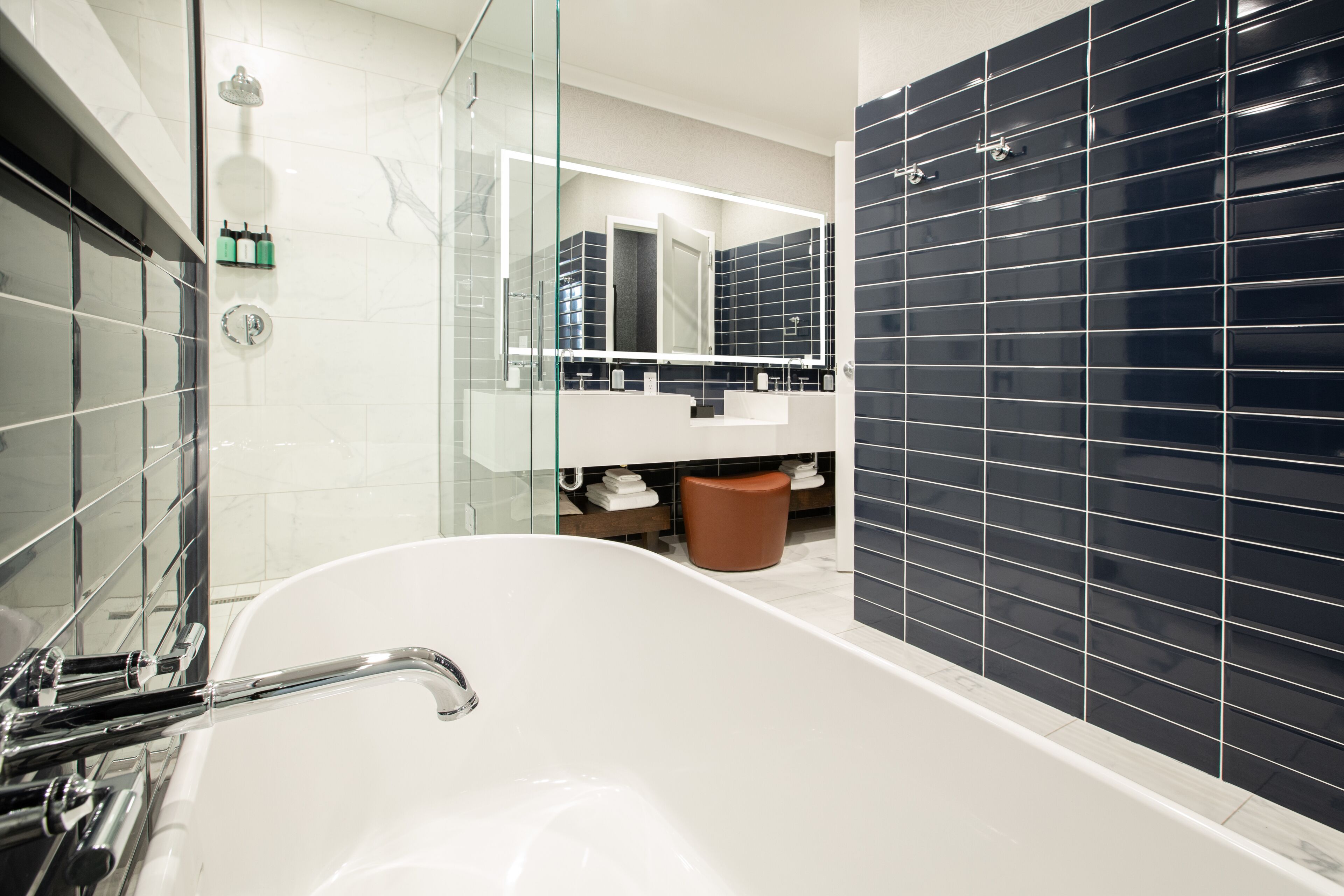 A modern bathroom with a freestanding bathtub, a glass-enclosed shower, and a large mirror above the sink.